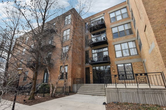 Front view of a multi-story brick apartment building with balconies.
