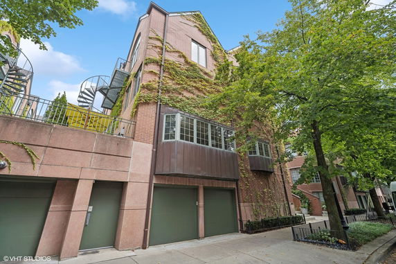Front view of a multi-story brick building with spiral staircase and garage doors.