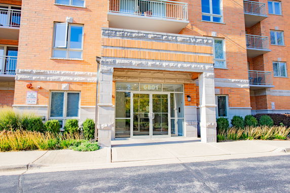 Front view of a brick apartment building entrance with glass doors.