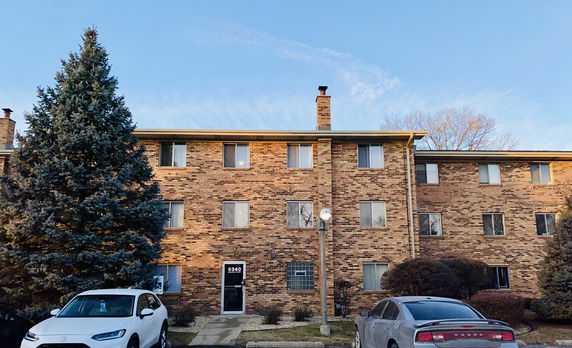 Front view of a multi-story brick building with multiple windows and an entrance door.