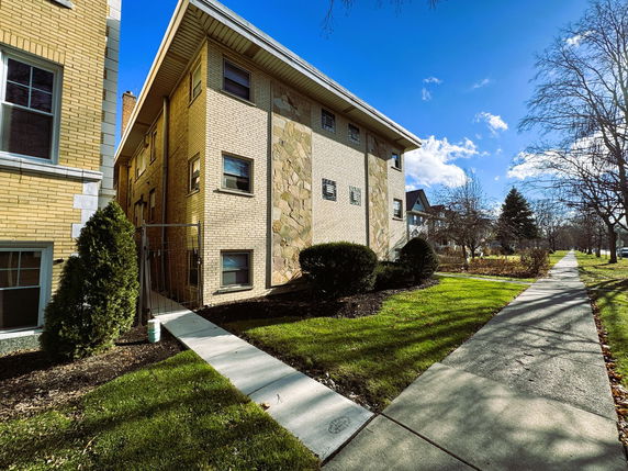 Front view of a brick building with a side entrance and walkway.