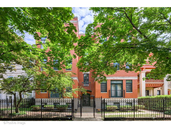 Front view of a multi-story brick building with decorative black fencing.