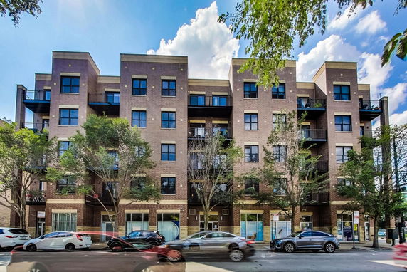 Front view of a multi-story brick apartment building with balconies.