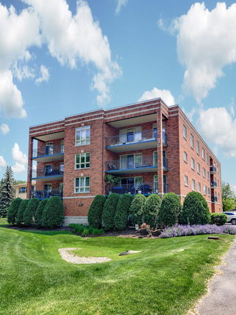 Front view of a multi-story brick apartment building with balconies.