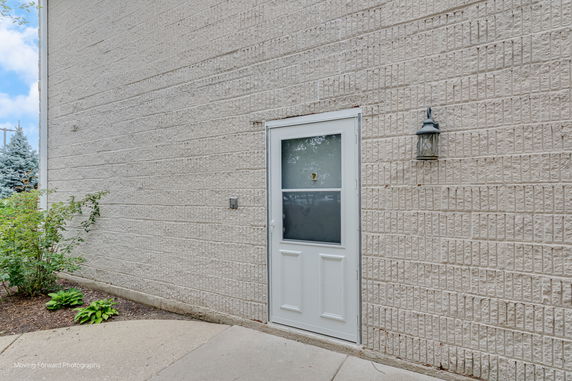 Side view of a building with a textured brick wall and a white door.