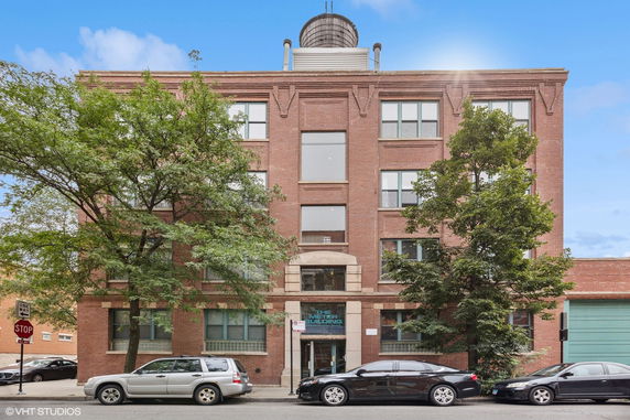 Front view of a multi-story brick building with a rooftop water tank.