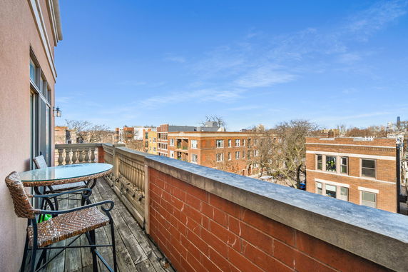 View of surrounding buildings from a balcony with a table and chairs.