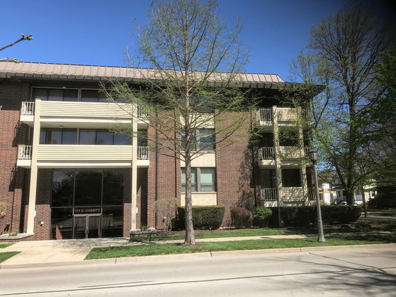 Front view of a multi-story brick building with balconies and central entrance.