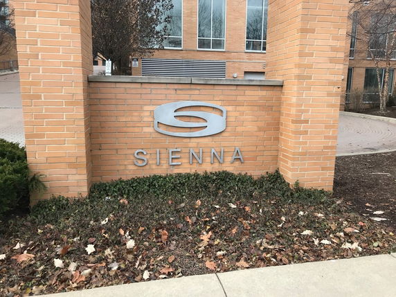 Front view of a building with a brick exterior and a sign that reads 'Sienna'.