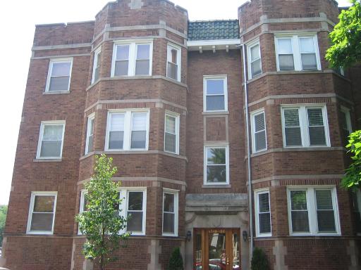 Front view of a multi-story brick building with bay windows.