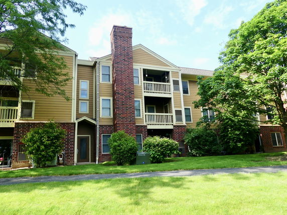 Front view of a multi-story apartment building with balconies and brick accents.