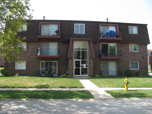 Front view of a three-story brick apartment building with small balconies.