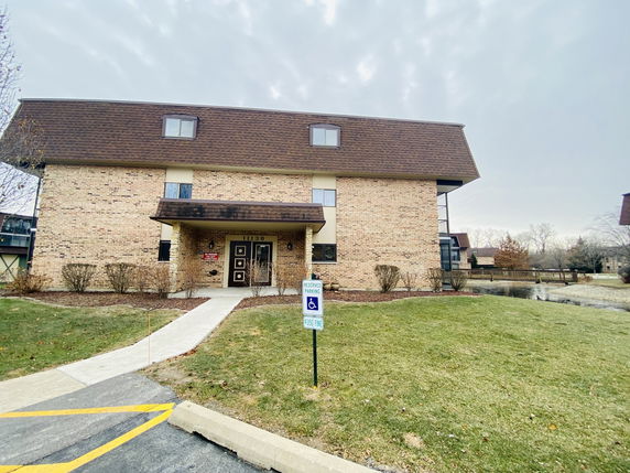 Front view of a multi-story brick building with a sloped roof and main entrance.