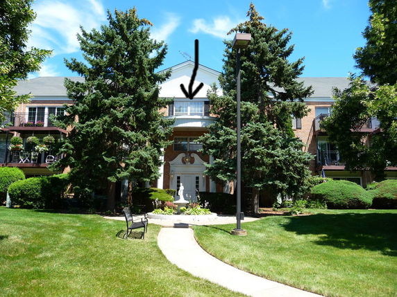 Front view of a multi-story building with balconies and brick facade.