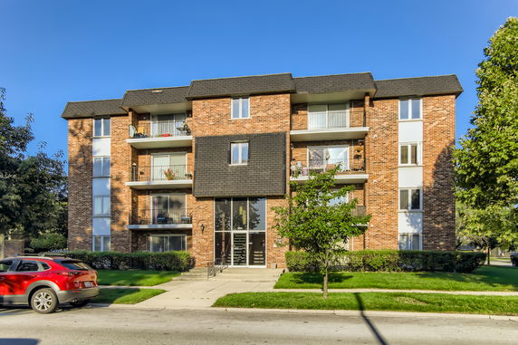 Front view of a multi-story brick apartment building with balconies.