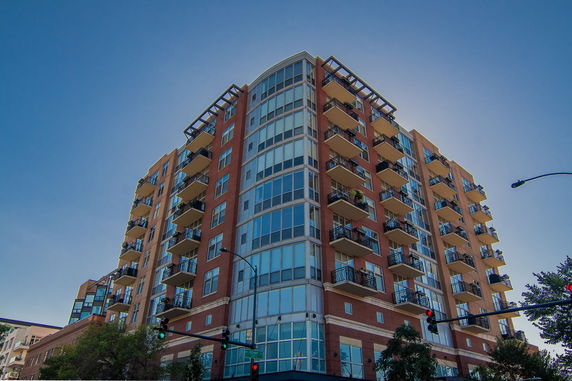 Front view of a multi-story apartment building with balconies and large windows.