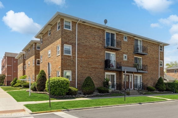 Front view of a multi-story brick apartment building with small balconies.