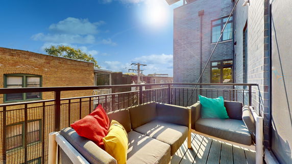 Outdoor balcony with seating and view of brick buildings.