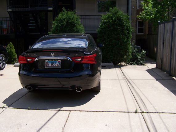Outdoor parking area with a parked car and nearby building.