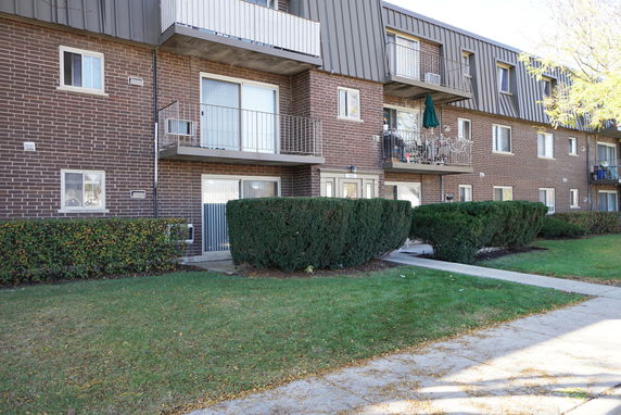 Front view of a three-story brick apartment building with balconies.