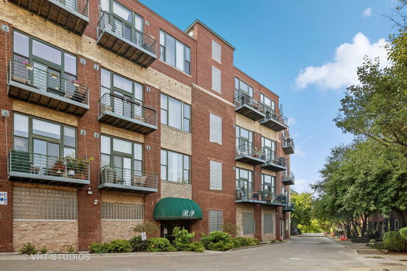 Front view of a multi-story brick apartment building with balconies.