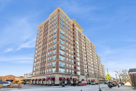 Front view of a multi-story brick building with large windows and storefronts on the ground level.