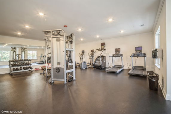 Room equipped with various gym equipment including treadmills and weight racks.