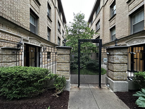 Front view of a multi-story brick building with gated entrance.
