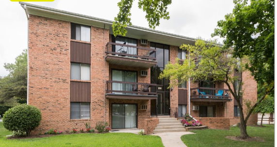 Front view of a multi-story brick apartment building with balconies.