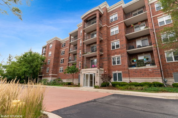 Front view of a multi-story brick apartment building with balconies.