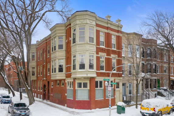 Front view of a multi-story brick building with ornate detailing on a street corner.