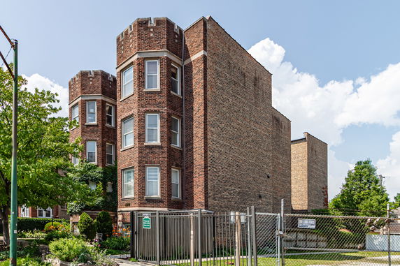 Front view of a multi-story brick building with distinctive turret-style corners.