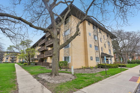 Front view of a multi-story brick apartment building with balconies.