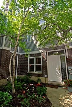 Front view of a two-story house with a brick facade and white entrance door.