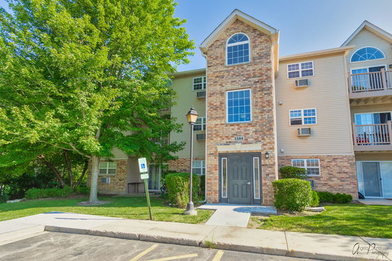 Front view of a multi-story residential building with brick and siding exterior.