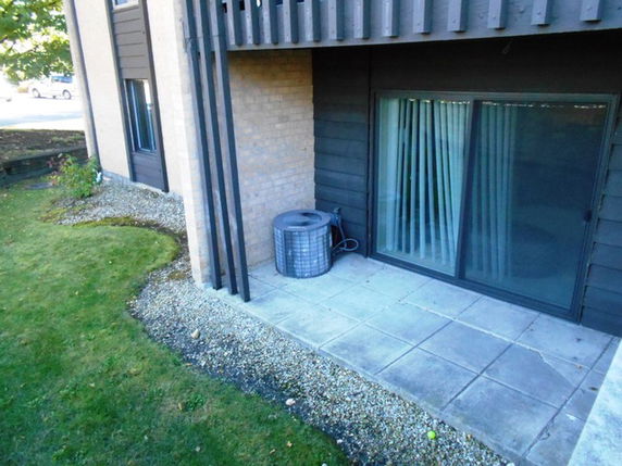 Exterior view of a building with a patio area and sliding glass door.