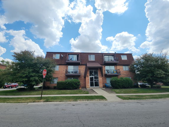 Front view of a three-story apartment building with balconies and a central entrance.