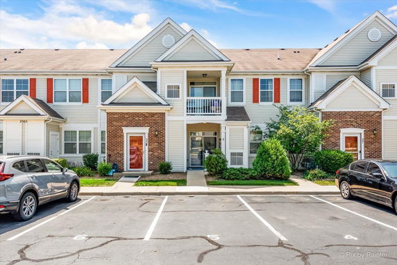 Front view of a two-story residential building with multiple entrances and parking spaces.
