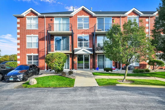 Front view of a multi-story brick apartment building with balconies.