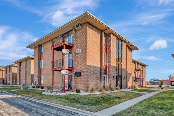 Front view of a multi-story brick apartment building with balconies.
