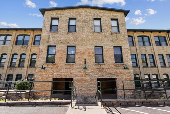 Front view of a multi-story brick building with several windows and doorways.