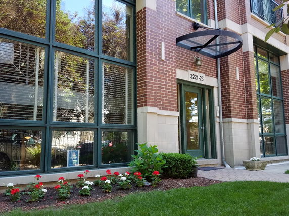 Front view of a multi-story brick building with large windows and entrance.