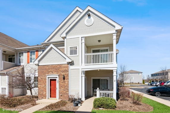 Front view of a two-story residential building with a balcony and brick accent.