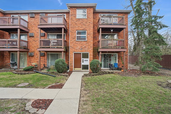 Front view of a multi-story brick apartment building with balconies.