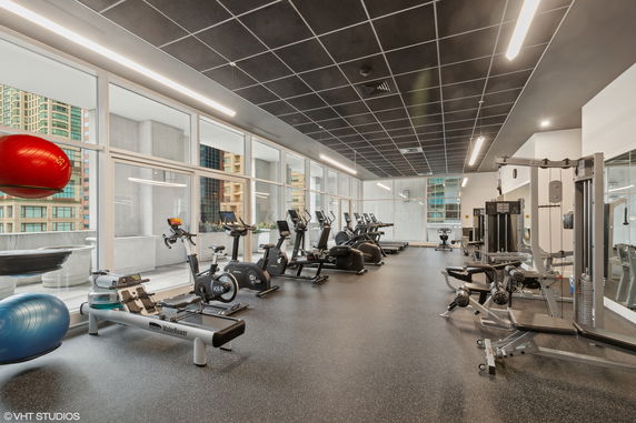 Interior view of a gym with exercise equipment and large windows.