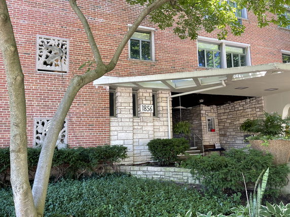 Front view of a brick building with decorative elements and an entrance canopy.