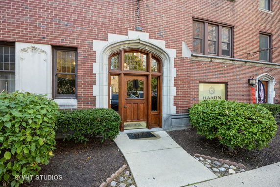 Front view of a brick building with an arched wooden doorway and windows.