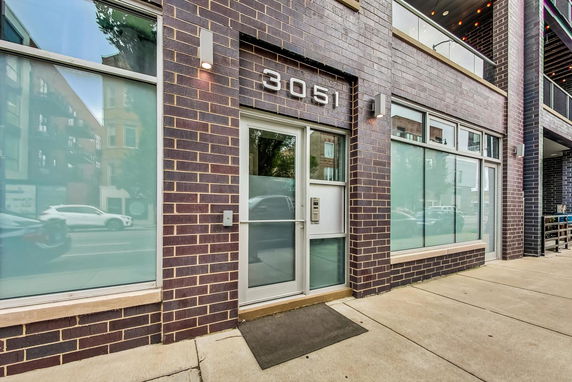 Front view of a brick building with a glass door and large windows.