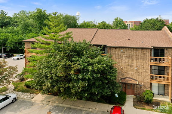 Front view of a multi-story brick building with a pitched roof and balconies.