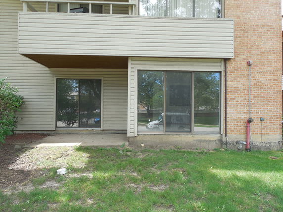 Front view of a multi-story house with sliding glass doors and brick siding.
